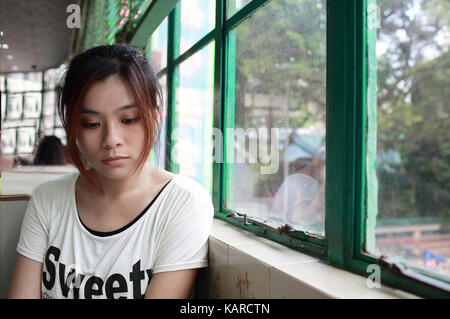 Femme triste en attendant quelqu'un qui est en retard, après avoir pleurer,elle regarde par la fenêtre voisine, réflexion sur lunettes dans restaurant de Hong Kong Banque D'Images