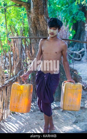 Fermier birman transportant des seaux remplis d'eau dans un village près de Bagan Banque D'Images