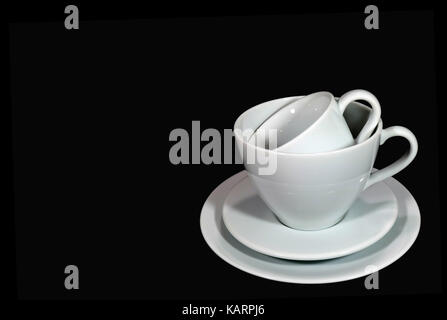 De taille différentes tasses à café en porcelaine blanche avec soucoupes entassées sur fond noir Banque D'Images