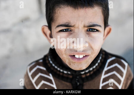 Portrait d'un garçon à la recherche jusqu'à l'appareil photo dans le village de Merzouga, Maroc Banque D'Images
