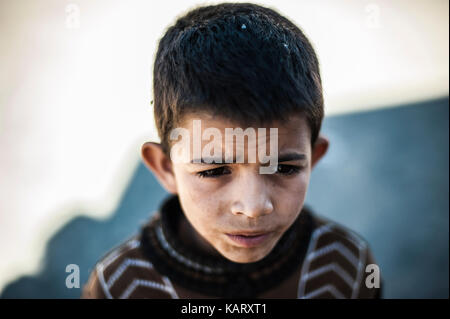 Portrait d'un garçon à la recherche jusqu'à l'appareil photo dans le village de Merzouga, Maroc Banque D'Images