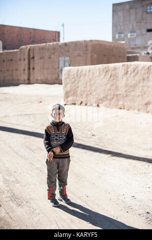 Portrait d'un garçon à la recherche jusqu'à l'appareil photo dans le village de Merzouga, Maroc Banque D'Images