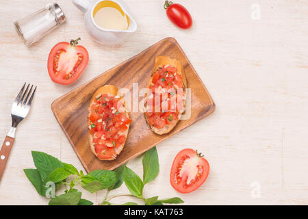 La préparation de délicieux plats italiens Bruschetta aux tomates avec des morceaux de légumes, herbes et l'huile Banque D'Images