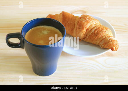 Une tasse de café avec un croissant au beurre servi sur plaque blanche Banque D'Images