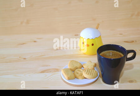 Une tasse de café et une assiette de biscuits servis sur la table en bois avec mignon poussin pot sucre Banque D'Images