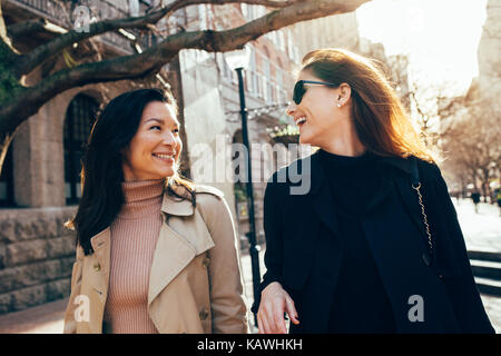 Deux femmes à l'extérieur d'avoir du plaisir. Les amis de marche dans la rue et souriant à l'extérieur. Banque D'Images