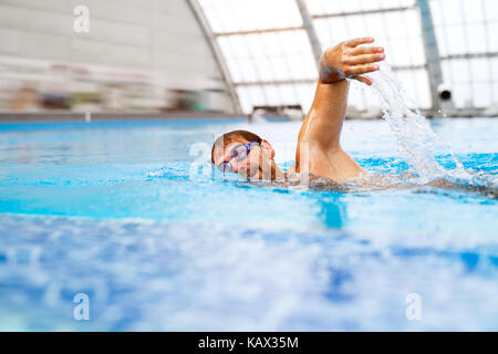 L'homme nage dans une piscine couverte. Banque D'Images