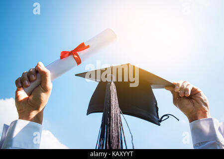 Le jour de la remise des diplômes, des images de diplômés célèbrent leur diplôme mis de main, un certificat et un chapeau à la main, sentiment de bonheur, date, cong Banque D'Images