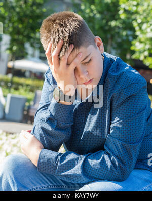 Triste adolescent assis sur street Banque D'Images