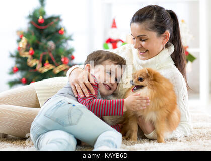 Mère de famille et son fils jouer avec chien à l'arbre de Noël Banque D'Images