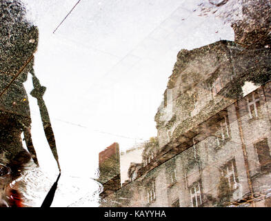 Ombre de réflexion silhouette d'une personne avec parapluie plié et un bâtiment dans la flaque Banque D'Images