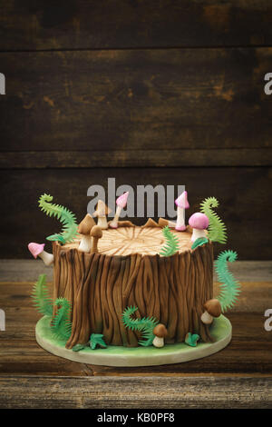 Forêt enchantée des forestiers du fondant gâteau avec un tronc d'arbre, de fougères, de champignons et de feuilles sur fond de bois avec copyspace Banque D'Images