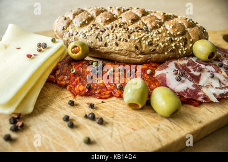 Village rustique, petit déjeuner avec des saucisses, jambon, olives, poivre noir, l'ail, du fromage et du pain fait maison. Banque D'Images