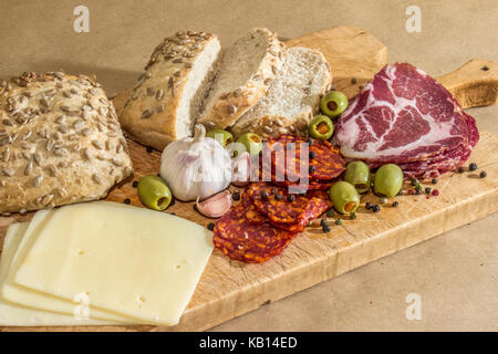 Village rustique, petit déjeuner avec des saucisses, jambon, olives, poivre noir, l'ail, du fromage et du pain fait maison. Banque D'Images