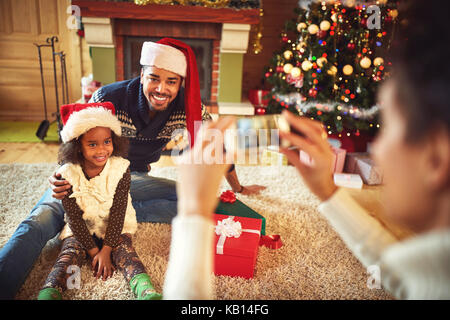 Mother taking picture of père et fille dans santa hats à Noël Banque D'Images