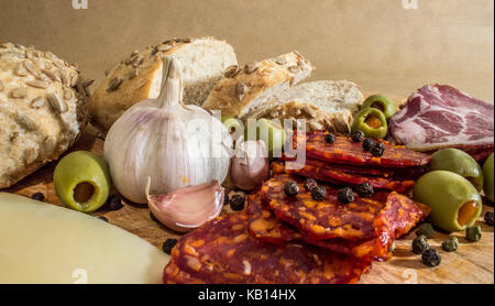 Village rustique, petit déjeuner avec des saucisses, jambon, olives, poivre noir, l'ail, du fromage et du pain fait maison. Banque D'Images