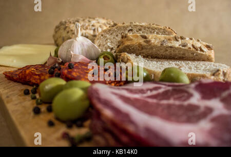 Village rustique, petit déjeuner avec des saucisses, jambon, olives, poivre noir, l'ail, du fromage et du pain fait maison. Banque D'Images