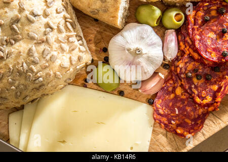 Village rustique, petit déjeuner avec des saucisses, jambon, olives, poivre noir, l'ail, du fromage et du pain fait maison. Banque D'Images