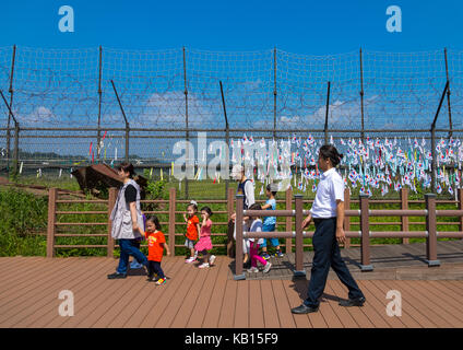 La famille de la Corée du sud passant devant les messages et de paix et d'unité à gauche sur rubans écrit sur clôture à dmz, province du hwanghae du nord, à Panmunjom, Corée du Sud Banque D'Images