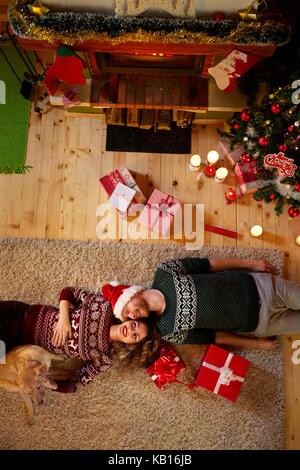 Jeune couple se trouvant sur le plancher pour Noël, vue du dessus Banque D'Images