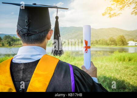 Il a diplômé hands up et célébrer avec certificat en main et il se sentir si le bonheur dans l'ouverture. Banque D'Images