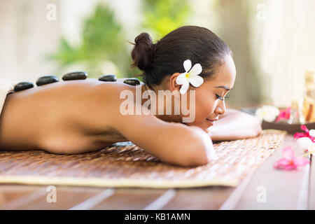 Femme balinaise bénéficiant en massage aux pierres chaudes au spa salon Banque D'Images