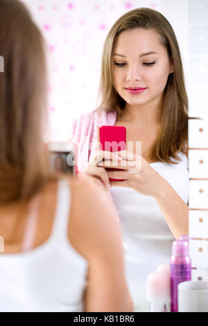 Jeune fille mignonne en tenant un miroir dans salle de bains avant selfies Banque D'Images