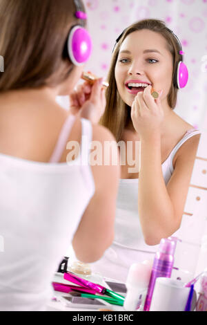 Teenage girl applying make up et à la recherche dans le miroir, joli adolescents s'amusant et en mettant le rouge à lèvres brillant à lèvres maquillage ou adolescent joyeux, Banque D'Images