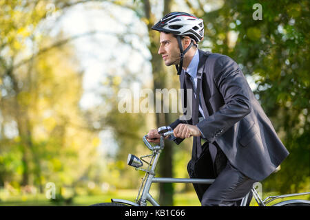 Jeune homme d'affaires pressé sur un vélo au travail Banque D'Images