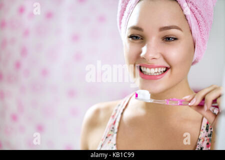 Smiling young girl se brosser les dents dans la salle de bains avant de mirror Banque D'Images