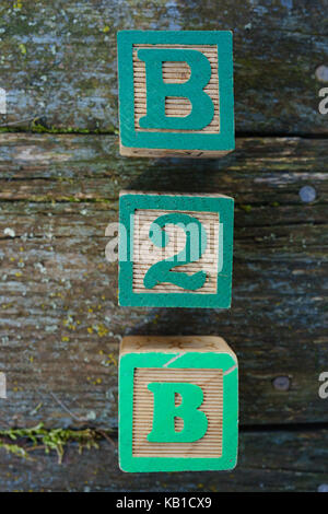 Jouet en bois pour enfants blocks spelling B2B sur un fond de bois. Banque D'Images