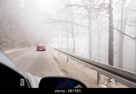 Virage sur route dans un épais brouillard Banque D'Images