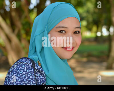 Belle, jeune femme musulmane de Malaisie, le port d'un hijab turquoise élégante, jetant le célèbre sourire malais Banque D'Images