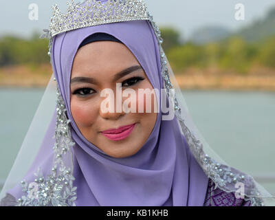 Belle Mariée Malais musulmans traditionnels élaborés avec le maquillage, le port d'un hijab mariée bleu clair avec microphone et de mariée robe de mariage bleu Banque D'Images
