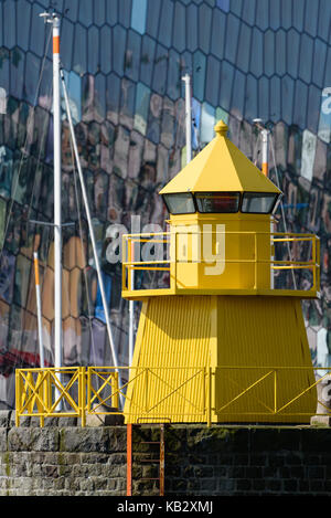 Phare dans le jaune, l'Islande Reykjavik Harbour avec façade en verre coloré et abstrait de l'harpa concert sur l'arrière-plan avec des réflexions je Banque D'Images