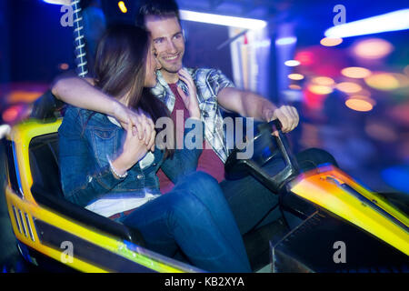 Jeune couple roulant en voiture de bouclier, dodgem ride Banque D'Images