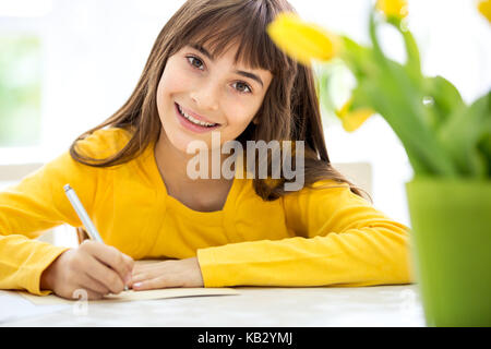 Cute little girl écrit ses devoirs à la table Banque D'Images