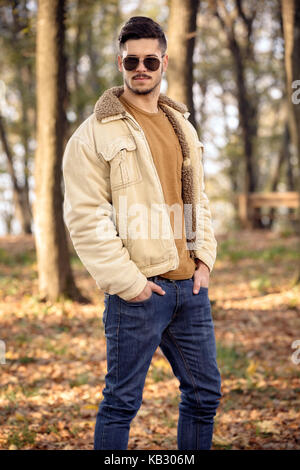 Jeune homme séduisant en automne en plein air portant des vêtements à la mode Banque D'Images