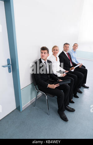 Groupe de candidats assis sur une chaise de bureau en entrevue donnant Banque D'Images