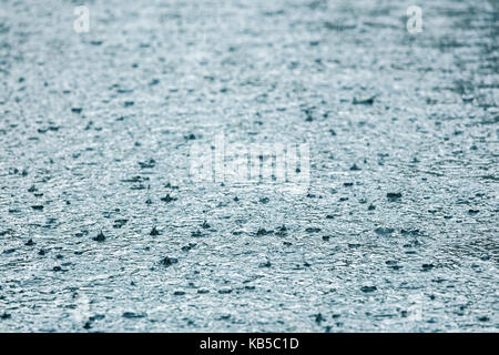 Asphalte inondées à l'eau et de gouttes de pluie éclabousse Banque D'Images