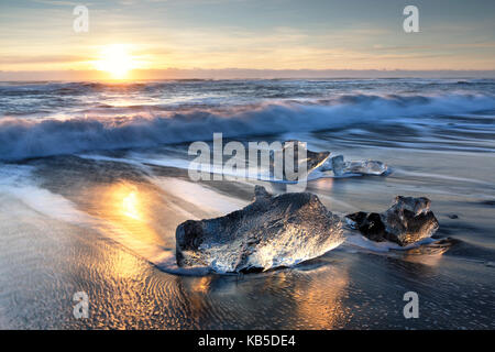 Morceaux de glace de glacier échoués sur une plage de sable volcanique noir, au lever du soleil près de jokulsarlon glacial lagoon, le sud de l'islande Banque D'Images