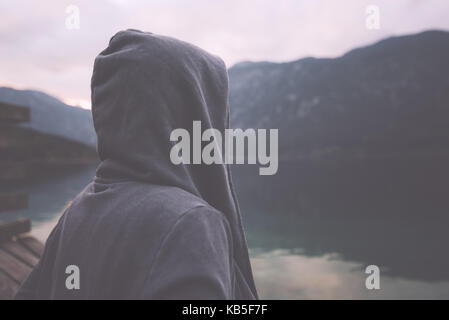 Portrait de nostalgique sombre triste mélancolique solitaire avec des femelles adultes Hooded Jacket debout sur la rive du lac Misty en couvert matin et de penser Banque D'Images