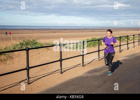 Femme qui court sur la promenade du front de mer à Crosby, Sefton, Merseyside. 28th septembre 2017. Météo Royaume-Uni. Journée ensoleillée sur l'estuaire de Mersey pendant qu'un jogger fait de l'exercice sur la vaste promenade de Mariners Way. Crédit; crédit: MediaWorldImages/Alamy Live News Banque D'Images