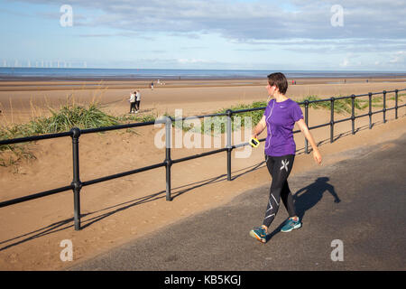 Femme qui court sur la promenade du front de mer à Crosby, Sefton, Merseyside. 28th septembre 2017. Météo Royaume-Uni. Journée ensoleillée sur l'estuaire de Mersey pendant qu'un jogger fait de l'exercice sur la vaste promenade de Mariners Way. Crédit; crédit: MediaWorldImages/Alamy Live News Banque D'Images