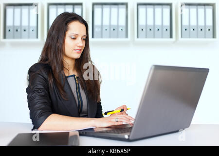 Portrait de belle jeune brunette business woman working on a laptop in office Banque D'Images