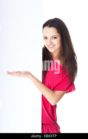 Jolie jeune femme en robe rouge showing blank signboard isolé sur fond blanc Banque D'Images