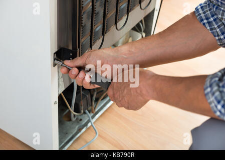 Portrait de militaire travaillant sur un réfrigérateur avec tournevis à la maison Banque D'Images