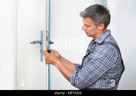 Male carpenter en verrouillage de fixation avec un tournevis porte à la maison Banque D'Images