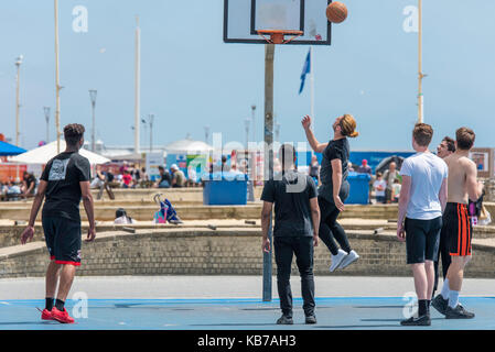 Les jeunes hommes jouant au basket-ball sur un d'une journée ensoleillée sur un front de mer de Brighton. Banque D'Images