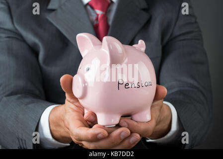 Portrait of businessman holding piggy bank avec écrit dessus pension Banque D'Images